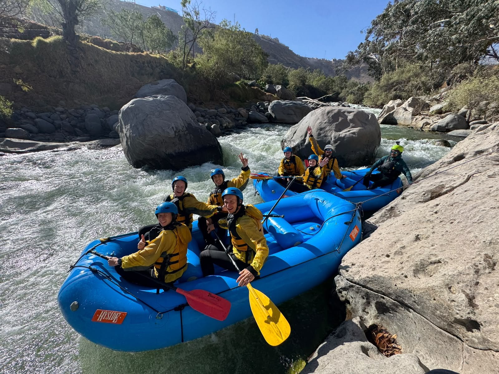 Grupo equipado para rafting en una balsa azul en el río Chili